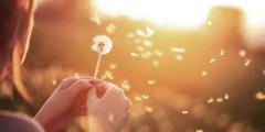 young-woman-playfully-blowing-a-dandelion.jpg
